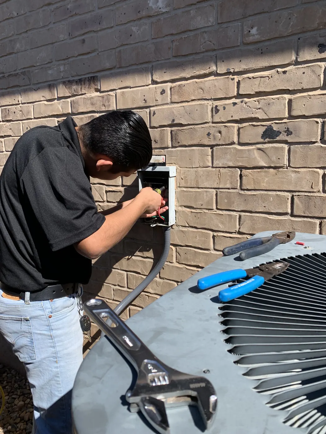 A Serrato technician servicing an outdoor air conditioning unit