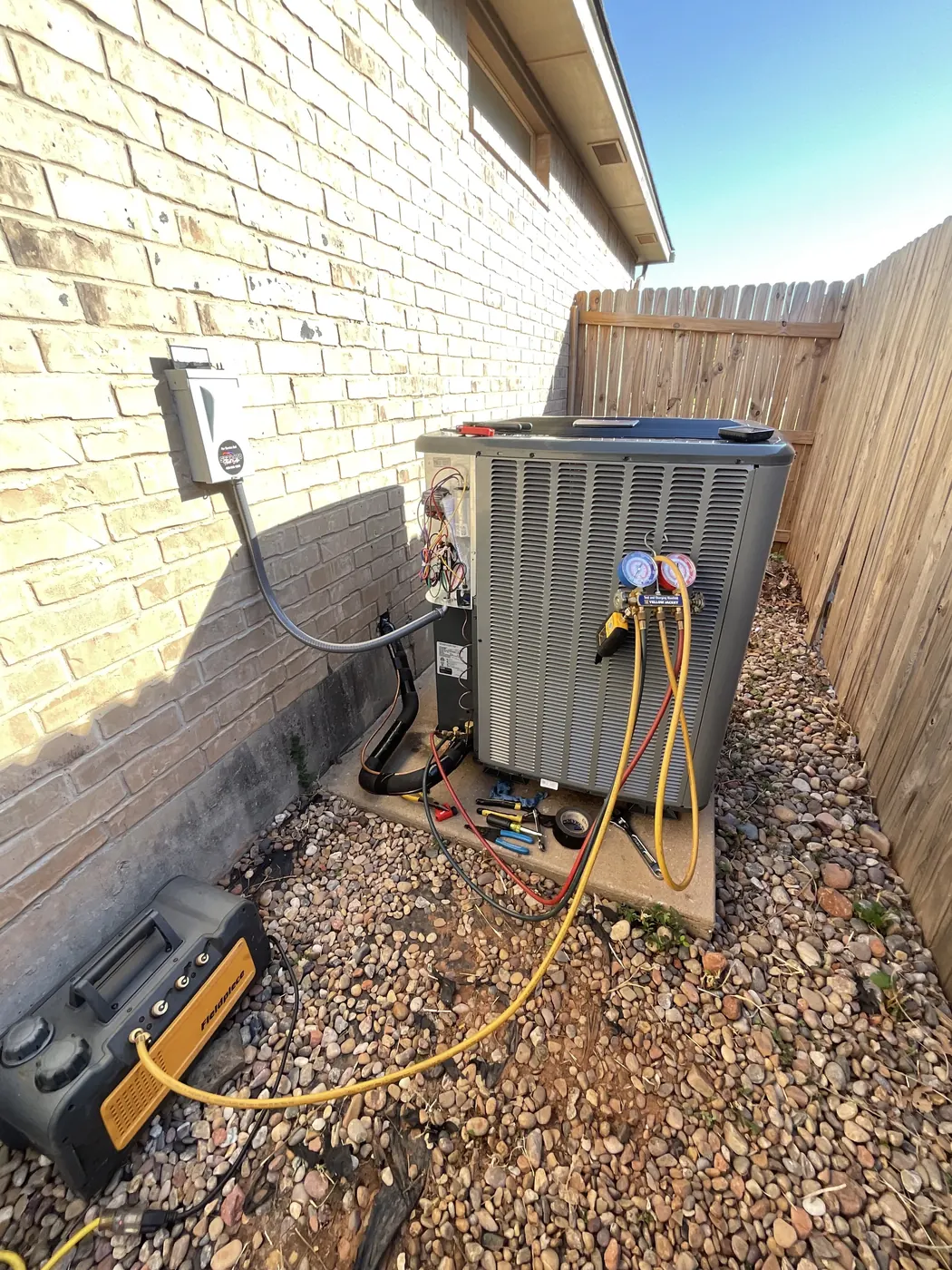 A technician checking refrigerant pressures on a home air conditioning system with gauges